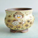 Ceramic cup with a duck design and sunflower patterns on a light blue background