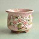 Pink ceramic pot with floral design on a light green background